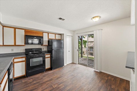 an empty kitchen with black appliances and a sliding glass door at Deerfield Apartments, Olathe, Kansas, 66062