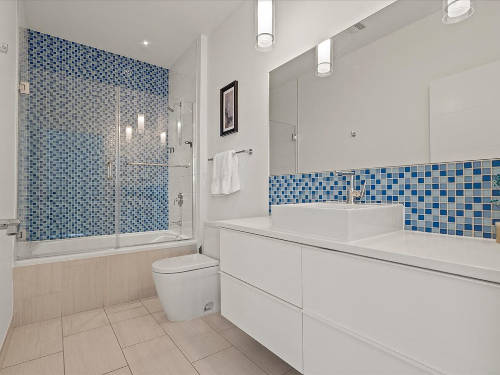a bathroom with white cabinets and blue and white tile at Sky On Main Apartments, Missouri