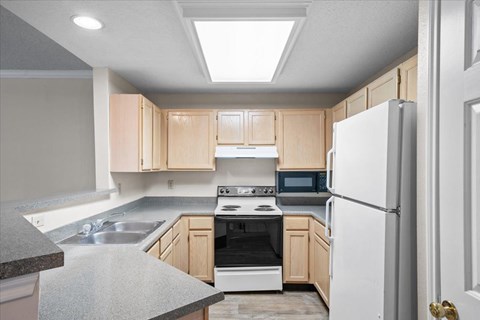 A kitchen with a white refrigerator, sink, and stove.