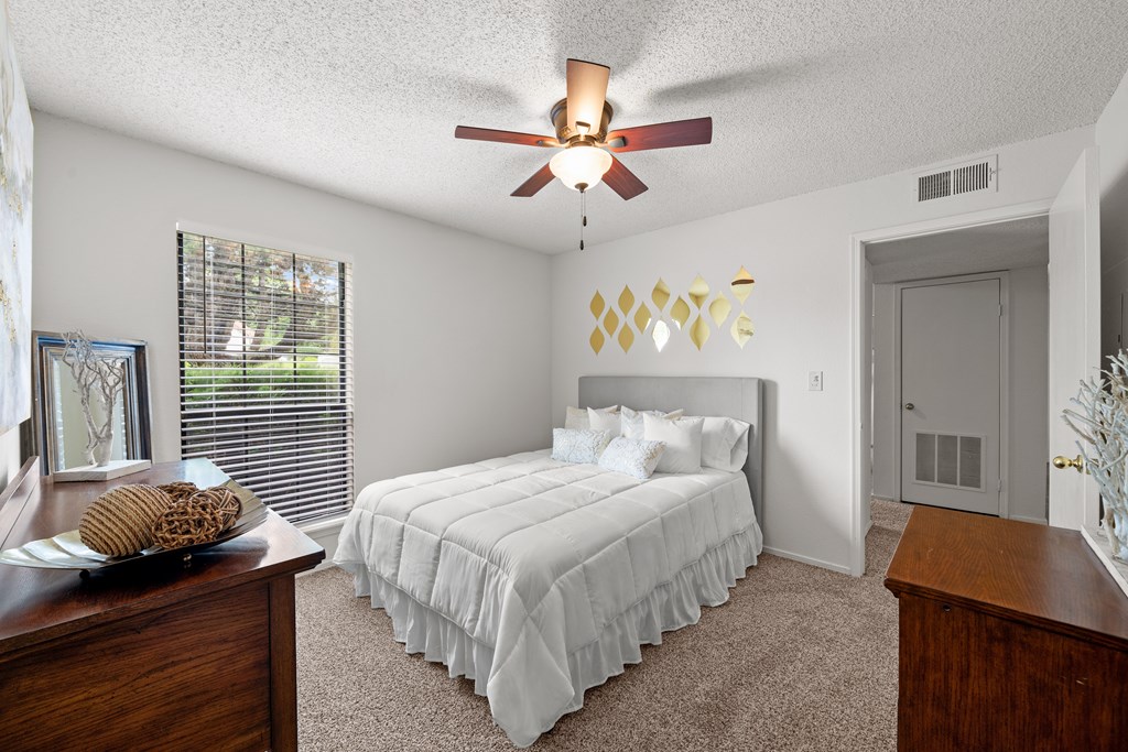 A bedroom with a bed, dresser, and ceiling fan. at Coventry Oaks Apartments, Overland Park, KS, 66214