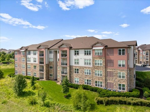 A large apartment building with multiple balconies and a green lawn in front.