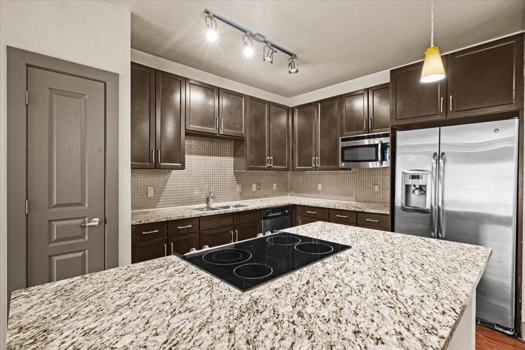 a kitchen with granite countertops and dark wood cabinets at Cypress at Lewisville Apartment Homes, Lewisville, TX