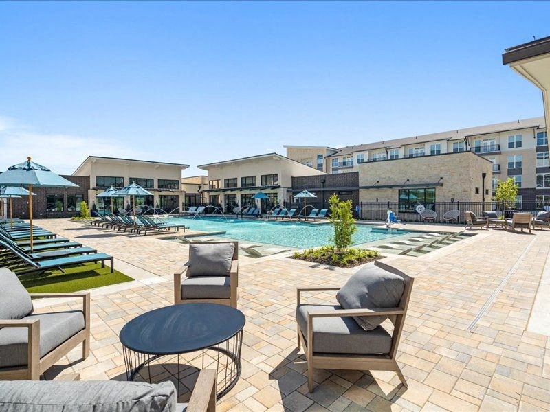 a swimming pool with chairs and umbrellas in front of a building