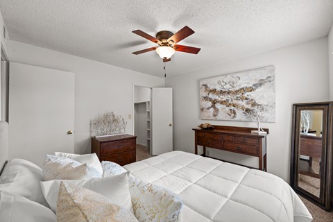 A bedroom with a large bed and a ceiling fan.