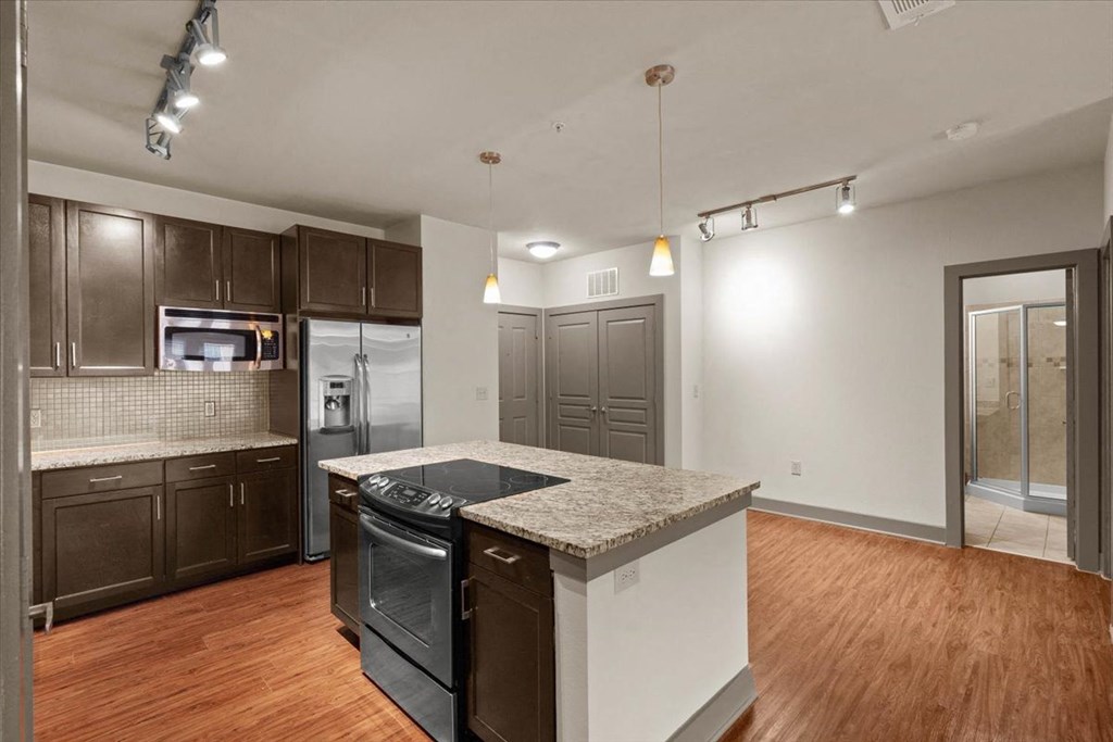 a kitchen with an island and a stove top oven at Cypress at Lewisville Apartment Homes, Lewisville, TX