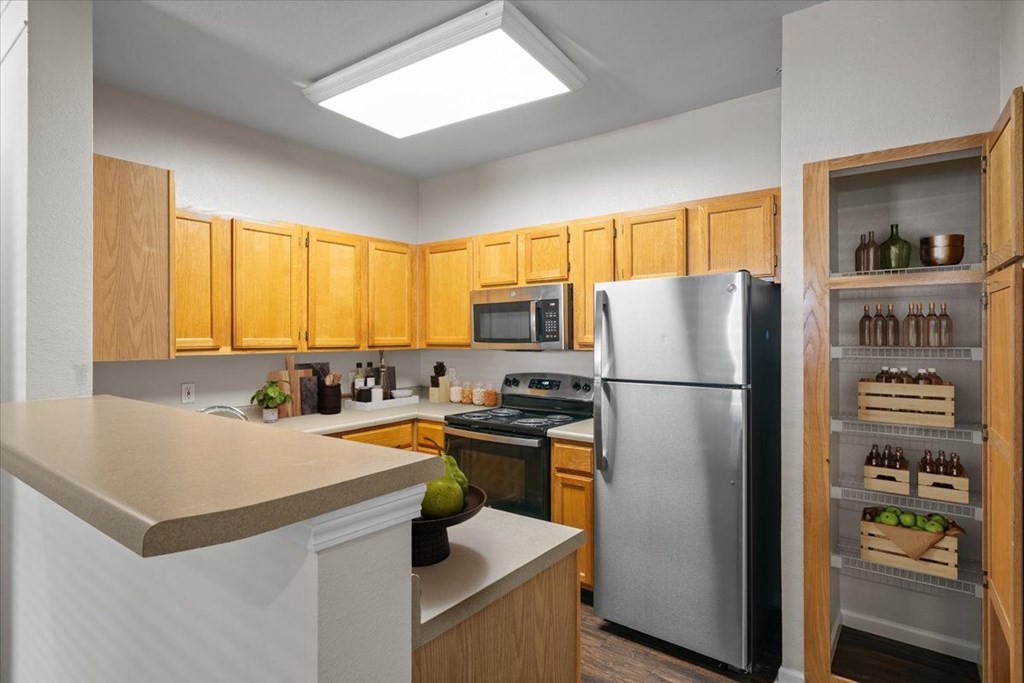 A kitchen with wooden cabinets and a stainless steel refrigerator. at Somerset Oaks Apartment Homes, Olathe, Kansas