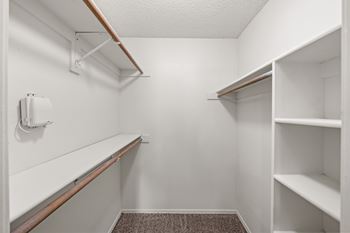 A white closet with shelves and a carpeted floor. at Coventry Oaks Apartments, Overland Park