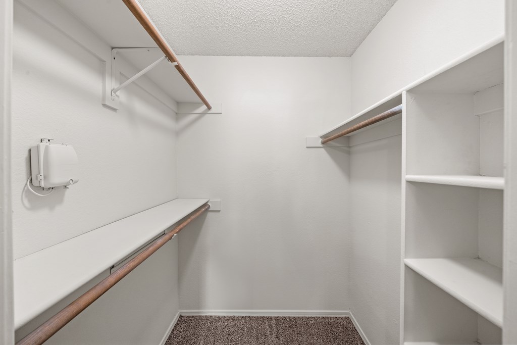 A white closet with shelves and a carpeted floor. at Coventry Oaks Apartments, Overland Park 66214
