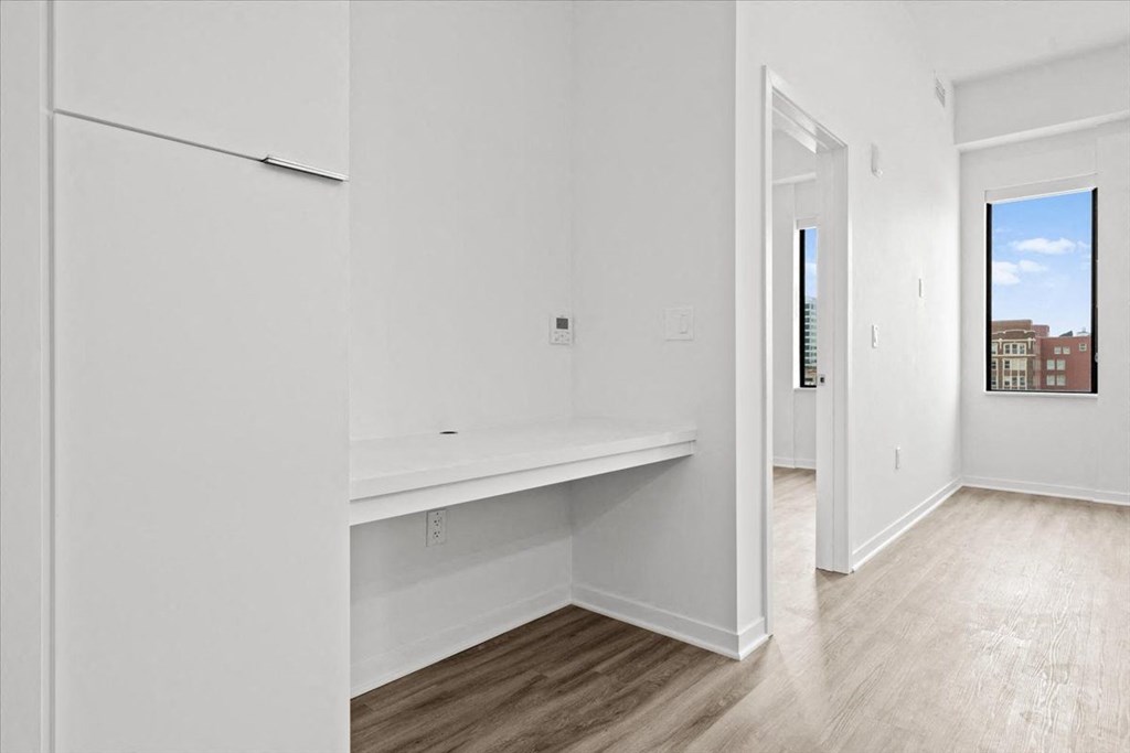 an empty room with white walls and a white refrigerator at Sky On Main Apartments, Missouri City