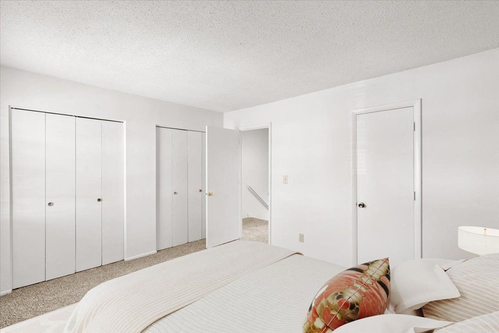 a white bedroom with a large bed and white closets