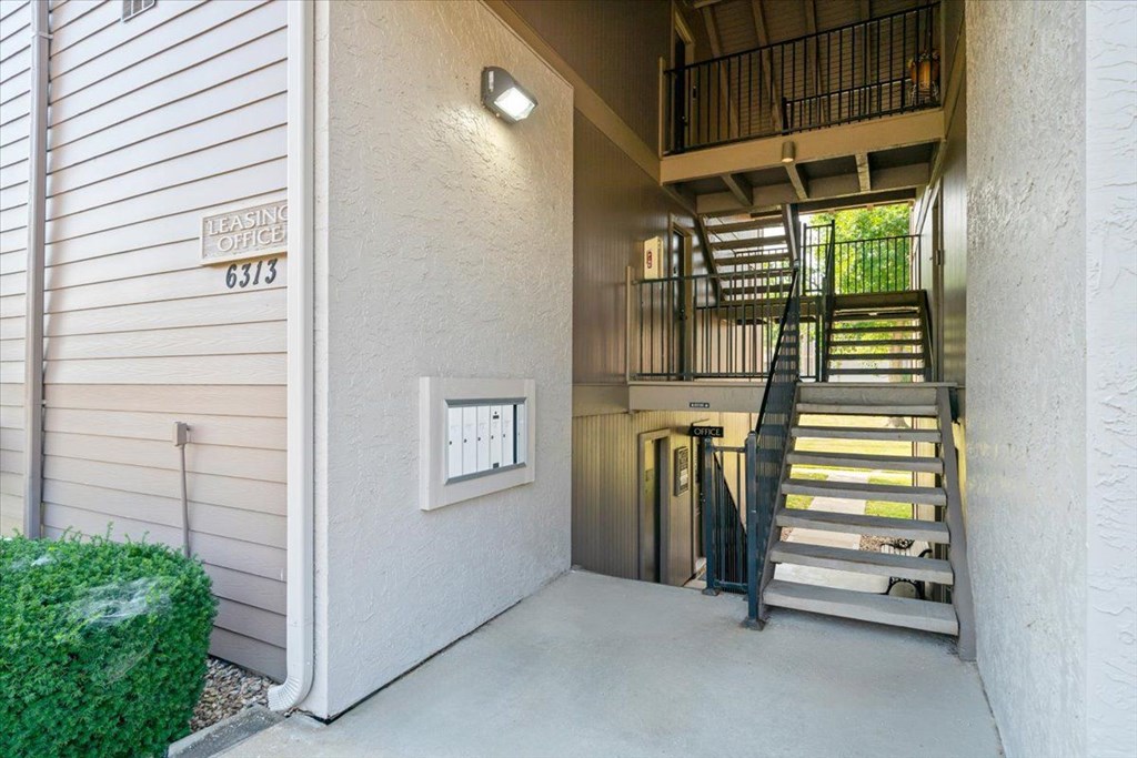 A staircase leads to a balcony in a building with a leasing office.