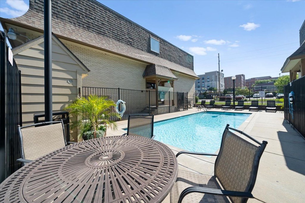 A patio with a table and chairs overlooking a pool. at Malvern Hill Apartment Homes, 66103, KS, 66214