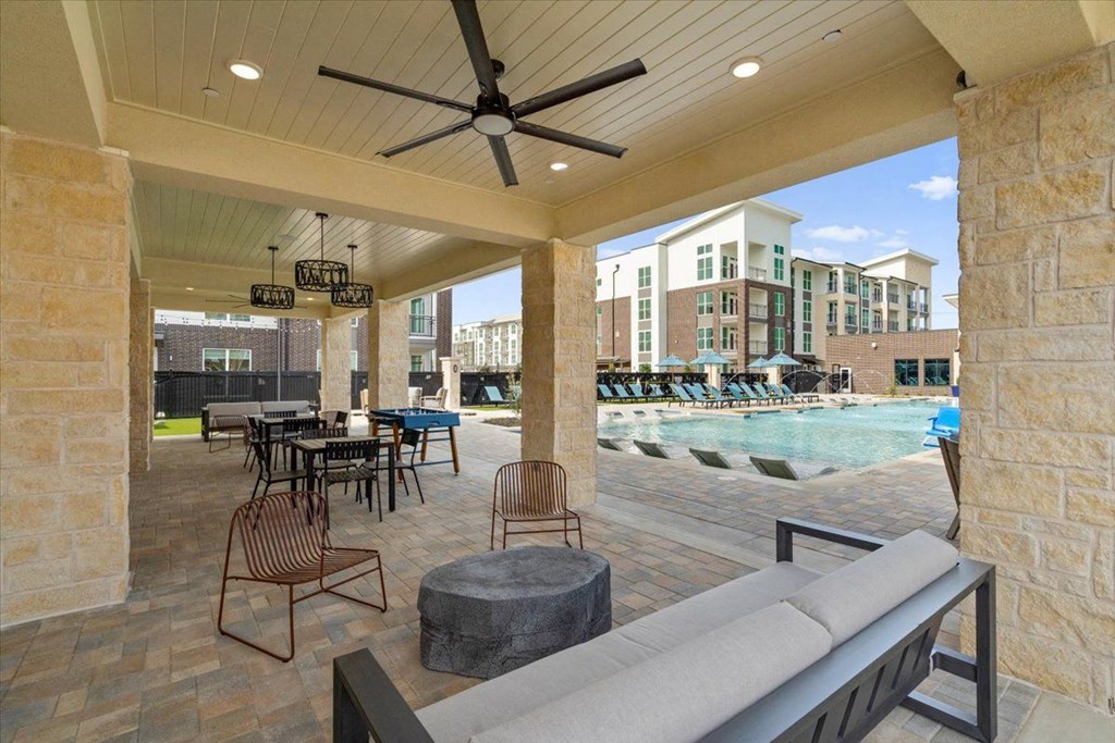a covered patio with a pool and chairs and tables