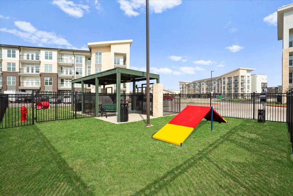 pet playground with a red and yellow slide and a black fence
