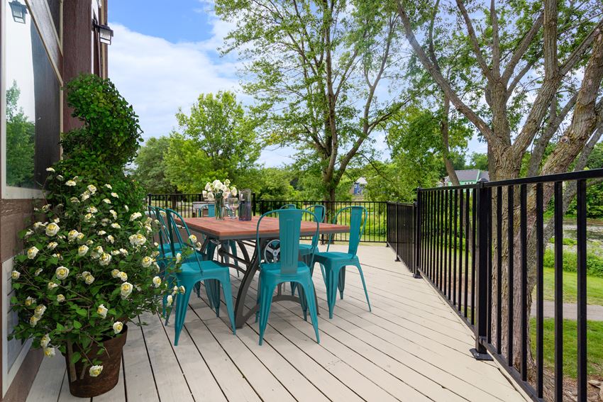a patio with a table and chairs on a wooden deck a patio with a table and chairs on a wooden deckat Millcreek Woods Apartments, Kansas, 66061 - Photo Gallery