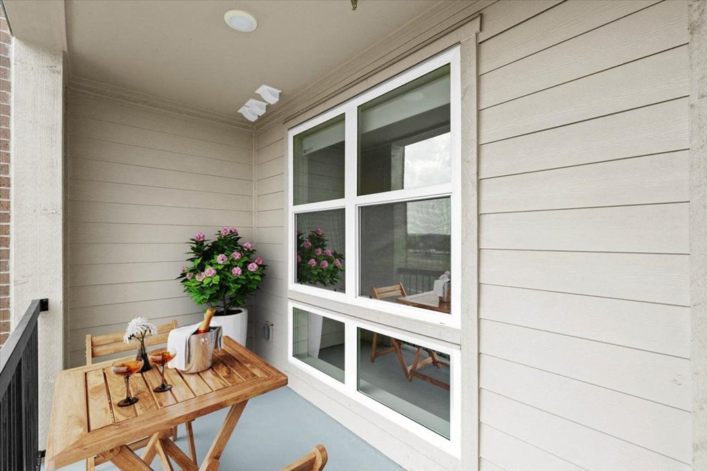 the porch of a home with a wooden table and chairs