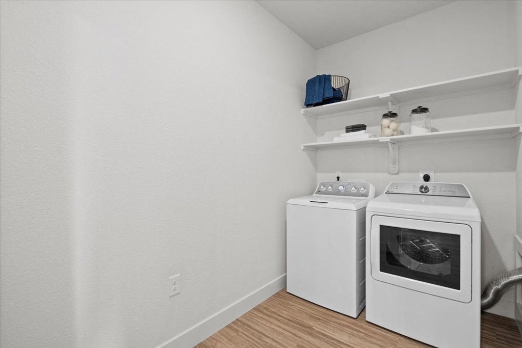 a white washer and dryer in a room with a washing machine and shelves