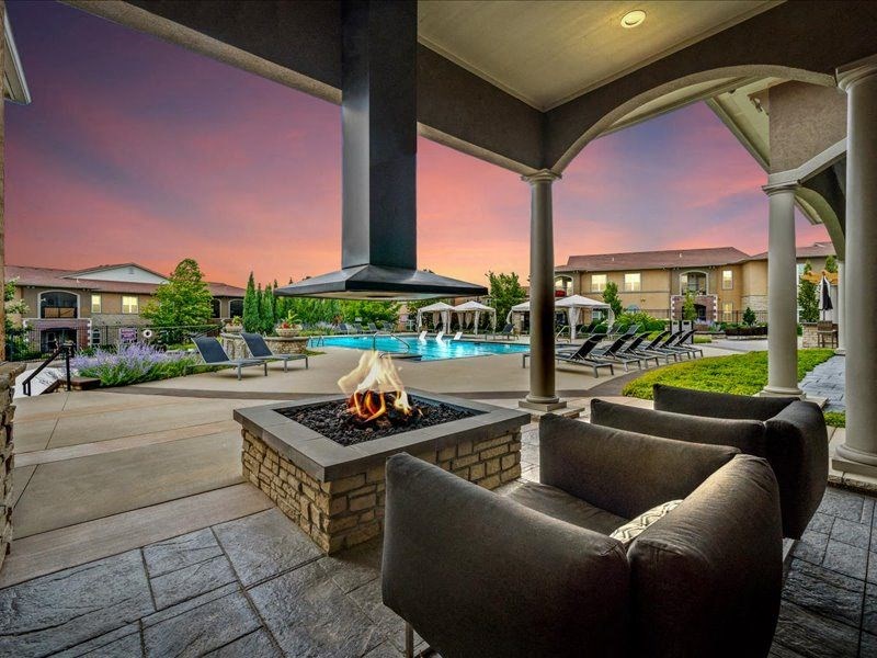 a patio with a fire pit and chairs and a pool