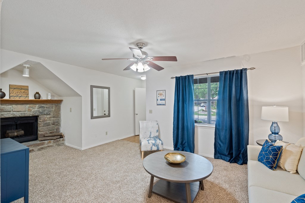 a living room with a fireplace and a ceiling fan at Waterford Place Apartments & Townhomes, Overland Park, 66210
