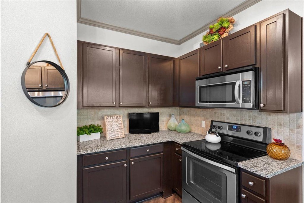 a kitchen with dark cabinets and stainless steel appliances