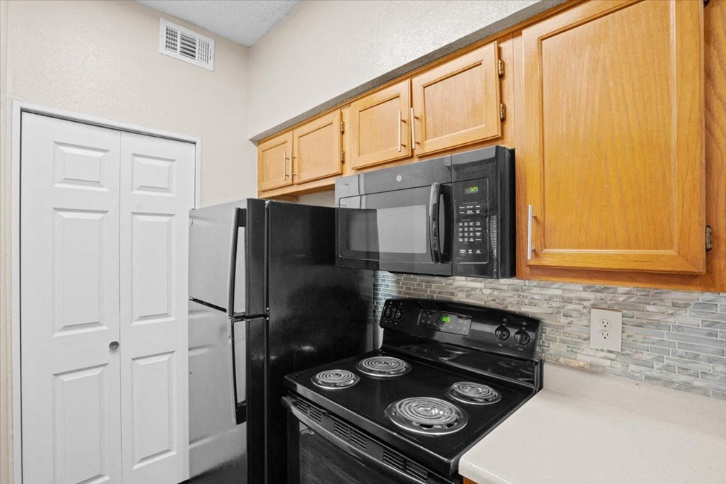 a kitchen with a stove top oven next to a refrigerator at Creekview Apartment Homes, Texas