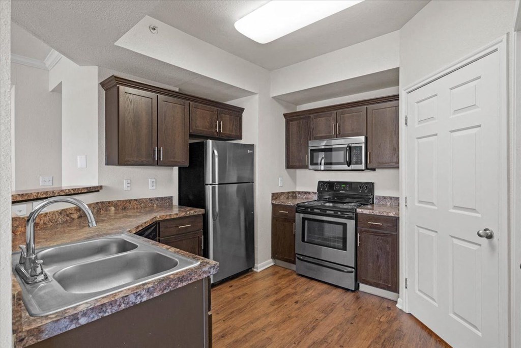 a kitchen with stainless steel appliances and wooden cabinets  at Crescent, Lenexa