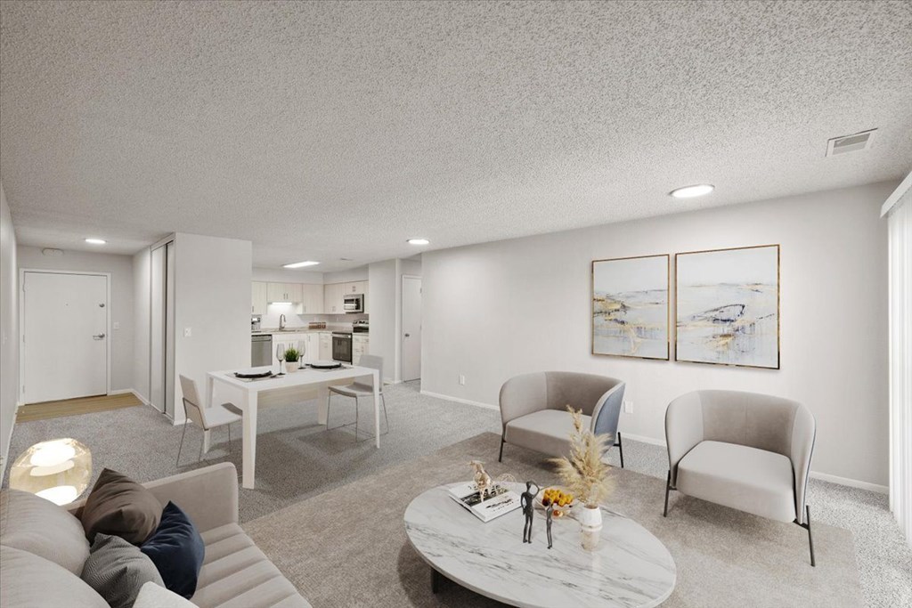 A living room with a white couch, a coffee table, and two chairs.