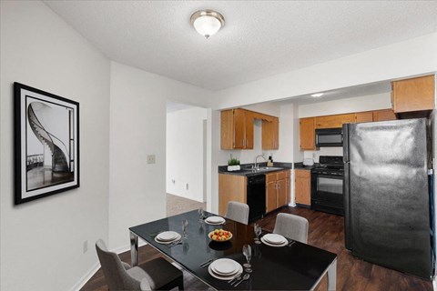 a kitchen and dining room with a black table and chairs at Deerfield Apartments, Olathe, Kansas, 66062