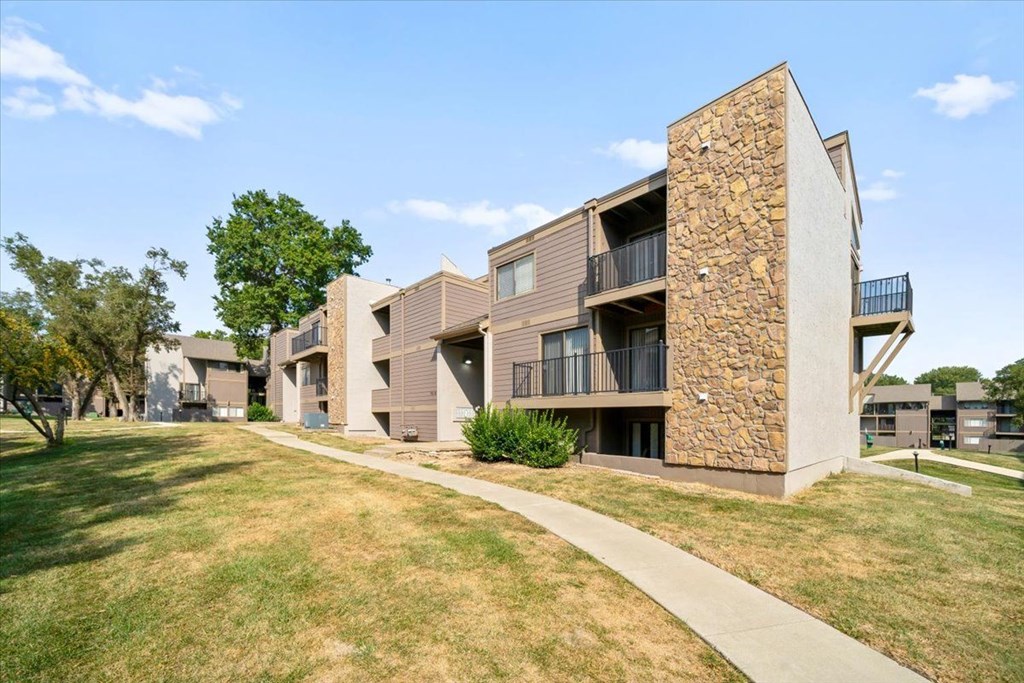 A modern apartment building with a stone facade and balconies.