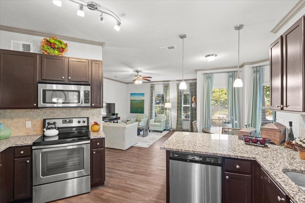 a kitchen and living room with wood floors and a ceiling fan