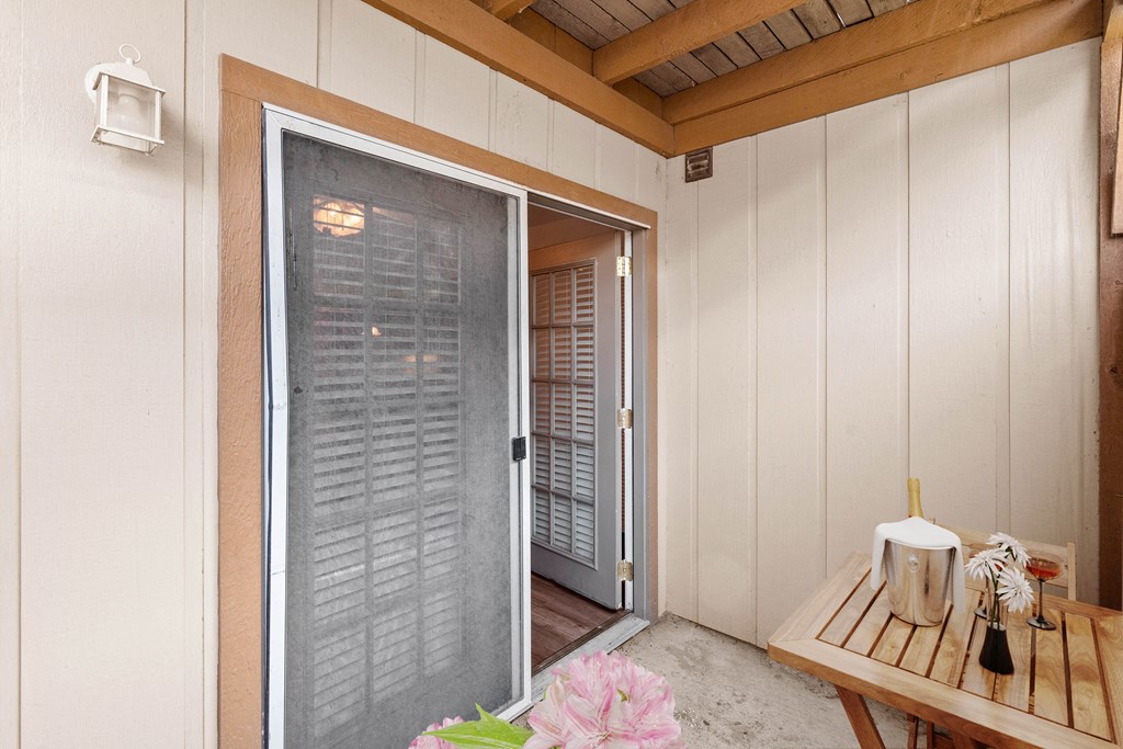 a patio with a sliding glass door and a table with a candle and flowers on it at Malvern Hill Apartment Homes, Kansas