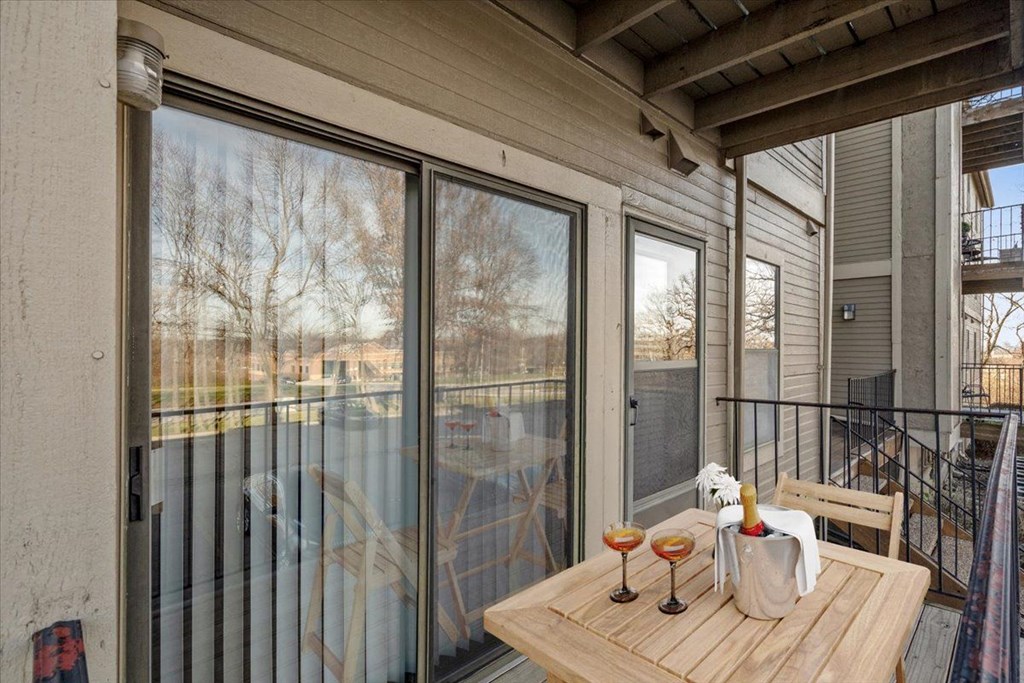a balcony with a table and two glasses of wine on it