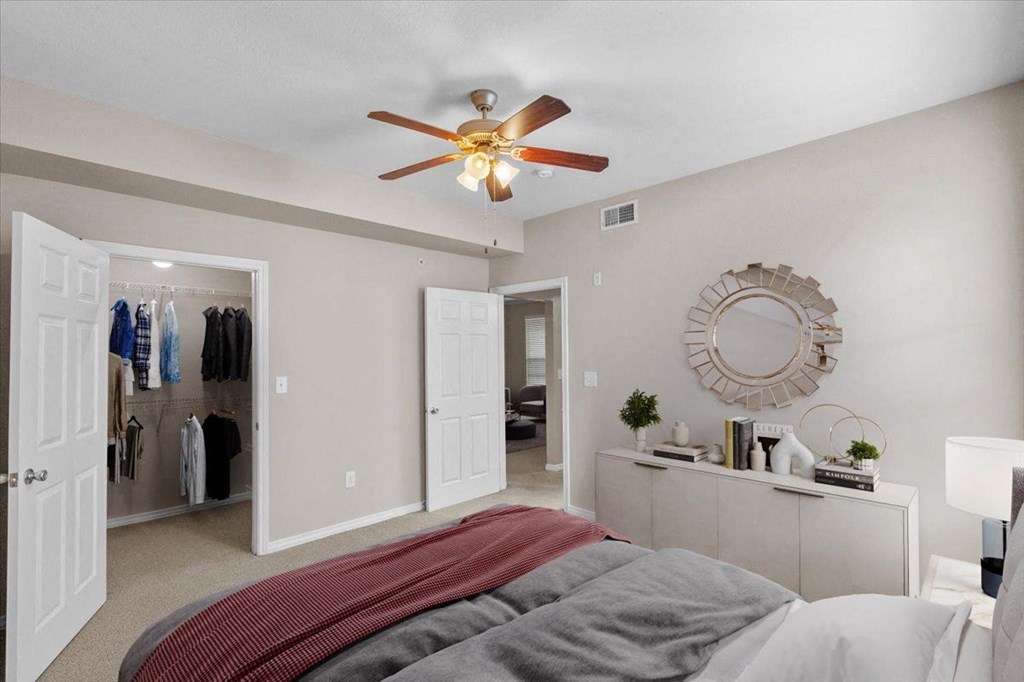 a bedroom with a large bed and a ceiling fan at The Clairborne Apartment Homes, Texas