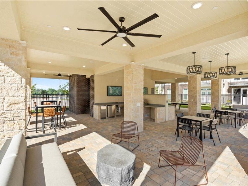 a large living room with tables and chairs and a ceiling fan