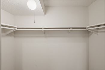 A spacious bedroom closet with a shelf, clothing rack and light at Bristol Pointe Apartments in Olathe, Kansas.