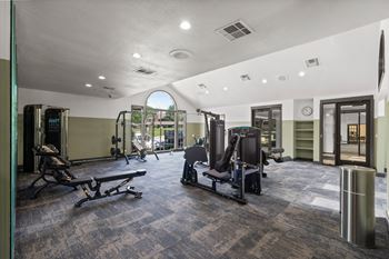 A gym with a variety of equipment including treadmills, weights, and exercise machines.