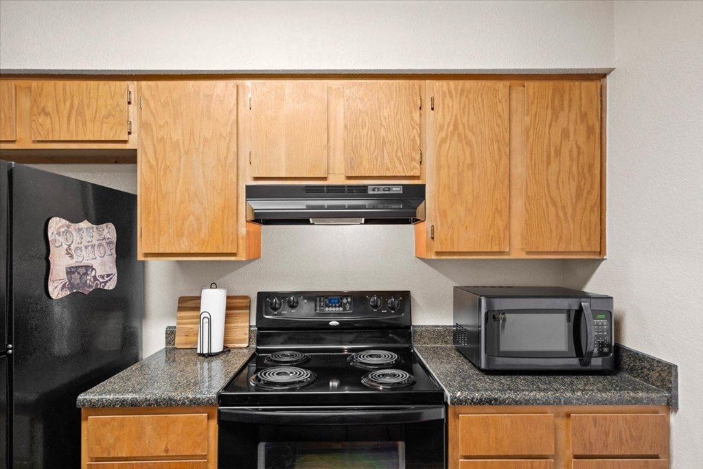 a kitchen with a stove microwave and cabinets at Wind River Lodge, Lenexa, 66219