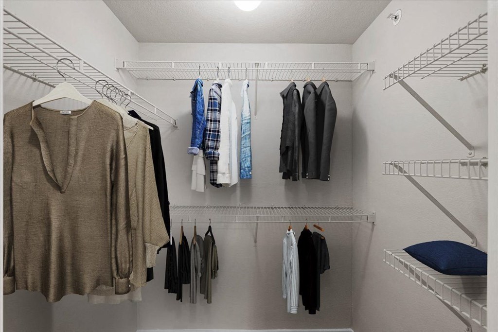 a walk in closet with a white closet and white shelves at The Clairborne Apartment Homes, Grand Prairie