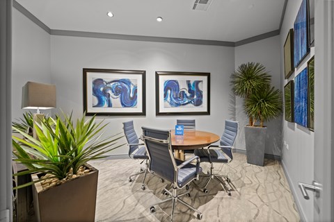 A conference room with a table, chairs, and two framed artworks on the wall.