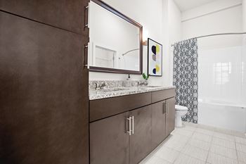 A bathroom with brown cabinets and a marble countertop.