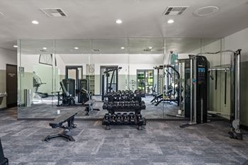 A gym with a variety of equipment including treadmills, weights, and exercise machines.