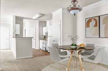 A dining room with a table set for two and a chandelier hanging from the ceiling. at Wynnewood Farms Apartments, Overland Park