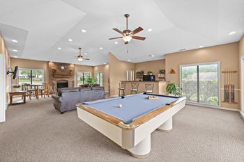A pool table is in the middle of a room with a ceiling fan. at Coventry Oaks Apartments, Overland Park, KS