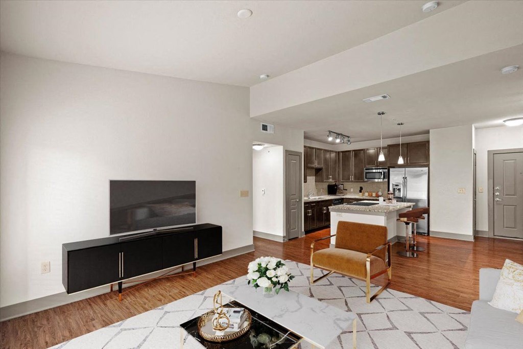 a living room with a fireplace and a kitchen in the background at Cypress at Lewisville Apartment Homes, Lewisville Texas