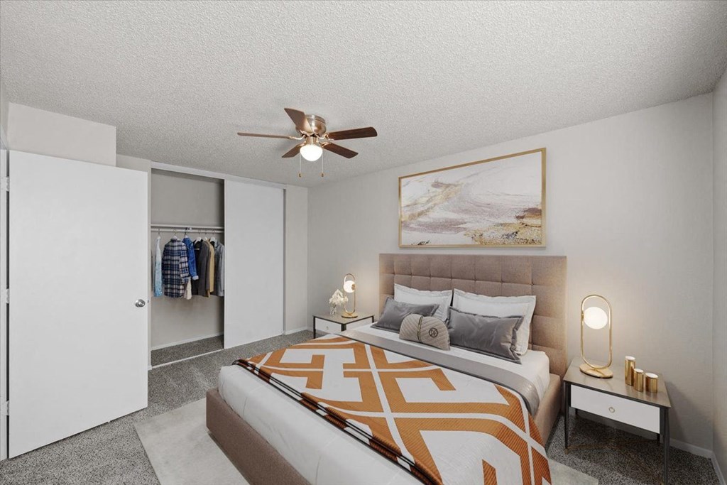 A bedroom with a bed, a ceiling fan, and a painting on the wall at Cloverset Active Adult Apartments, Kansas City 64114