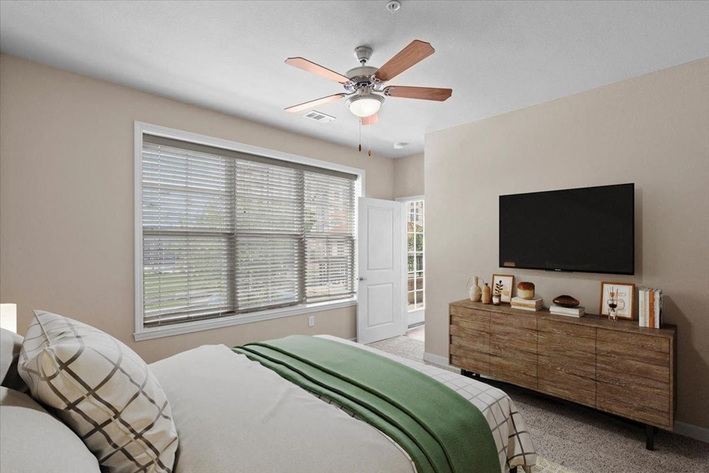 a bedroom with a large window and a ceiling fan