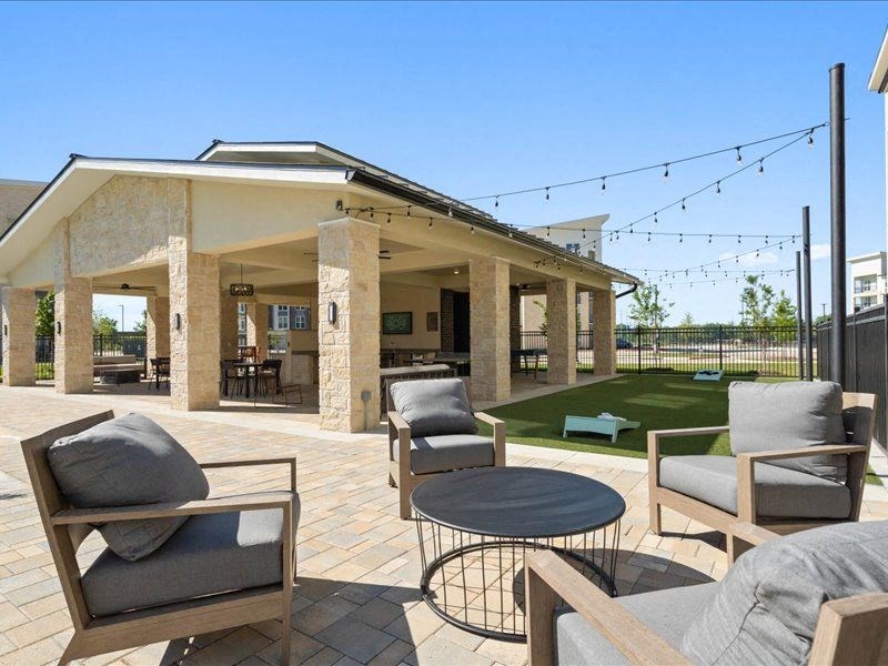 a covered patio with chairs and a lawn