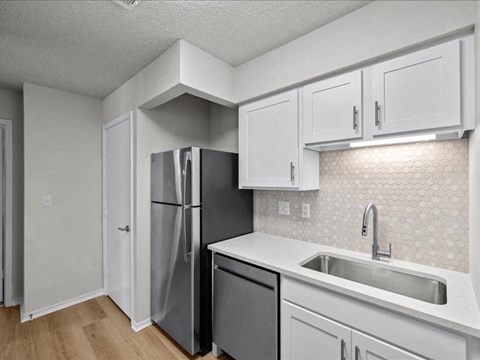 a kitchen with white cabinets and a stainless steel refrigerator at Highland Park Apartment Homes, Overland Park