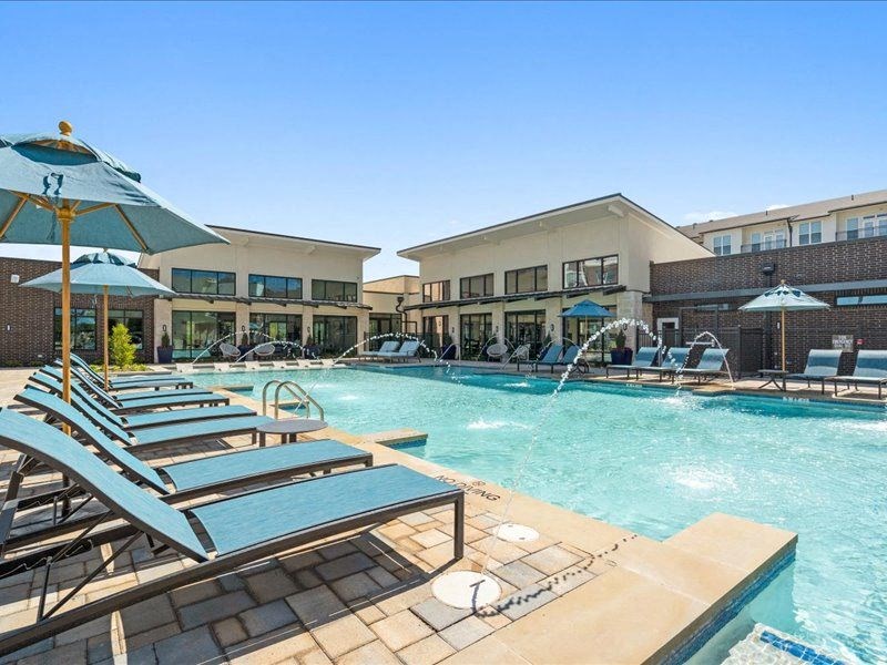 a swimming pool with lounge chairs and umbrellas