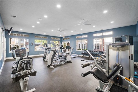 A spacious gym with a variety of equipment including treadmills, elliptical machines, and weight machines.